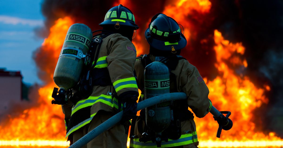 Two firefighters holding hose during big fire